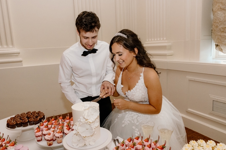 bride and groom cutting white floral cake