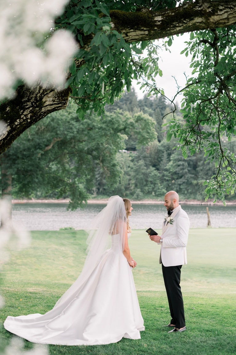 Bride and groom reading private vows underneath a tree